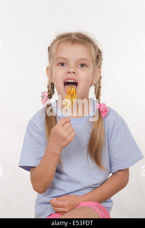 the five-year old girl enthusiastically eats candy Stock Photo