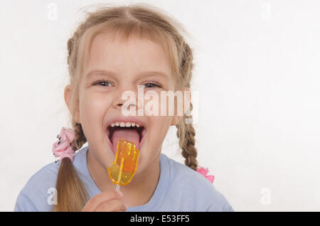 the five-year old girl enthusiastically eats candy Stock Photo