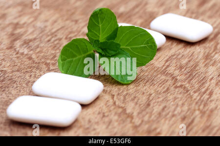 Chewing gum with mint leaves on wooden surface Stock Photo