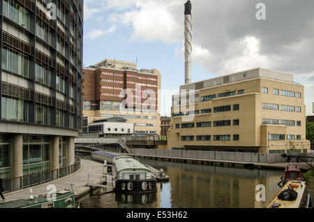 LONDON, ENGLAND  MAY 13, 2014: Narrow boats moored along the sides of Paddington Canal Basin with Queen Mary's Hospital to rear. Stock Photo