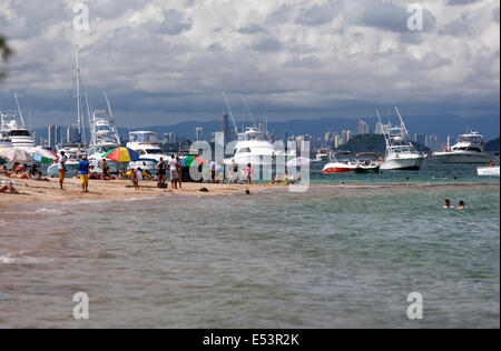 Tourist in the Taboga Island beach with yachts and Panama City skyline behind Stock Photo