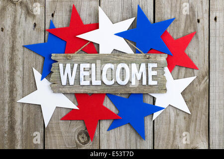 Welcome sign with red, white and blue stars hanging on rustic wooden background Stock Photo