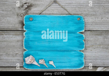 Blank teal blue sign with seashells hanging on rustic wooden background Stock Photo