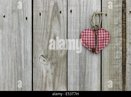 Key to my heart; red checkered (plaid) heart with brass skeleton key hanging on rustic wooden door Stock Photo