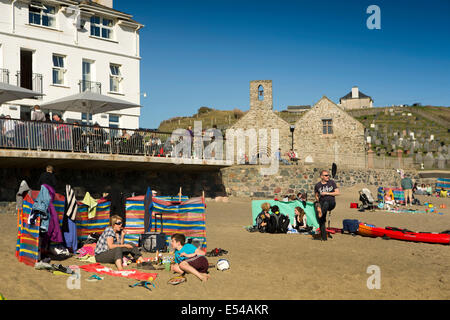 UK, Wales, Gwynedd, Lleyn peninsula, Aberdaron, holidaying families on the beach below St Hywyn’s Church Stock Photo