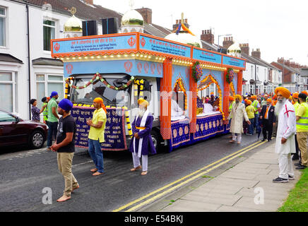 Middlesbrough, UK. 20th July, 2014. The annual Nagar Kirtan Parade celebrating Sikh culture in the North-east of England took place in Middlesbrough Cleveland UK today Sunday 20 July. The parade is led by five saffron robed men leading a float which carries the Guru Granth Sahib, the Sikh Holy Scripture.  Members of the procession are barefoot in deference to the scripture so displayed.  They are preceded by sweepers cleaning the road.  This picture shows the float carrying the Guru Granth Sahib, the Sikh Holy Scripture Credit:  Peter Jordan NE/Alamy Live News Stock Photo