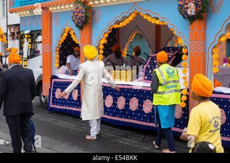 Middlesbrough, UK. 20th July, 2014. The annual Nagar Kirtan Parade celebrating Sikh culture in the North-east of England took place in Middlesbrough Cleveland UK today Sunday 20 July. The parade is led by five saffron robed men leading a float which carries the Guru Granth Sahib, the Sikh Holy Scripture.  Members of the procession are barefoot in deference to the scripture so displayed.  They are preceded by sweepers cleaning the road.  This picture shows the float carrying the Guru Granth Sahib, the Sikh Holy Scripture Credit:  Peter Jordan NE/Alamy Live News Stock Photo