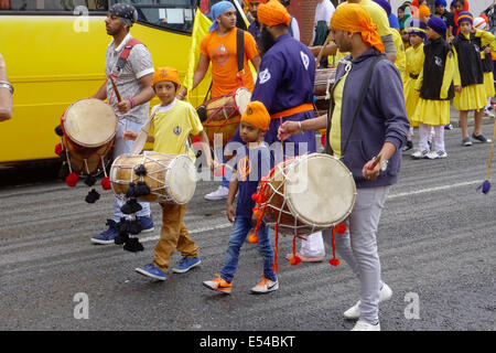 Middlesbrough, UK. 20th July, 2014. The annual Nagar Kirtan Parade celebrating Sikh culture in the North-east of England took place in Middlesbrough Cleveland UK today Sunday 20 July. The parade is led by five saffron robed men leading a float which carries the Guru Granth Sahib, the Sikh Holy Scripture.  Members of the procession are barefoot in deference to the scripture so displayed.  They are preceded by sweepers cleaning the road. This picture shows Sikh boys marching and playing drums in the parade Credit:  Peter Jordan NE/Alamy Live News Stock Photo