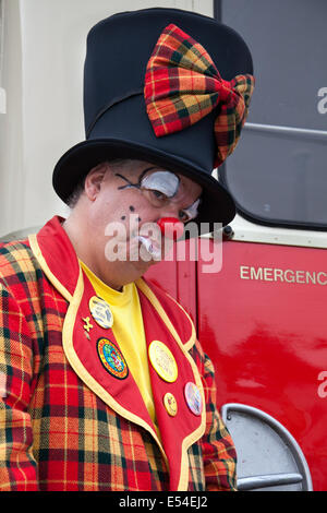 Professional Circus clown, fun, funny, happy, carnival, party, costume, humor, entertainment,  celebration, red face,  comic, colorful, character, art, wig.  Clowning in a funny art deco top hat and tartan suit in Fleetwood, Lancashire. Performer Paul Davies expressions of sadness, surprise & humor.  Colorful Clown costume and Children's Entertainer at the Festival of Transport, UK Stock Photo