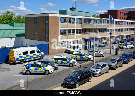 View from above looking down at assorted police cars and vans parked outside entrance to office building Basildon police station Essex England UK Stock Photo