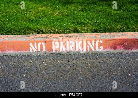 A red painted curb with a no parking warning sign Stock Photo