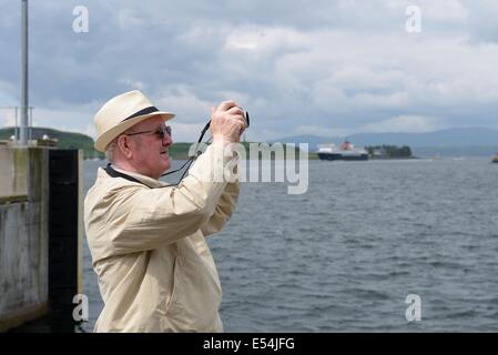 Mature gentleman taking picture with digital camera in Oban, Scotland Stock Photo