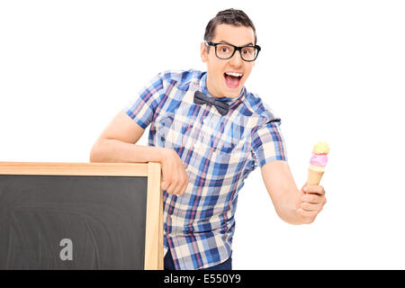 Young man holding an ice cream behind a blackboard Stock Photo