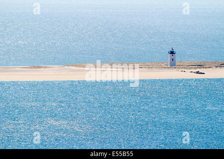 A lighthouse on the beach and surrounded by the ocean. Stock Photo
