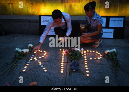 Kuala Lumpur, Malaysia. 21st July, 2014. A couple light up a candle as a memorial to MH17 tragedy in aceremony at the Kuala Lumpur City Centre(KLCC), Kuala Lumpur, Malaysia. The UN Security Council was expected on July 21 to adopt a resolution demanding that pro-Russian separatists grant unrestricted access to the site of the downed passenger jet in east Ukraine. Credit:  Khairil Safwan/Pacific Press/Alamy Live News Stock Photo