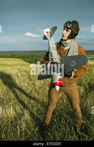 Young guy in vintage clothes pilot with an airplane model outdoors Stock Photo