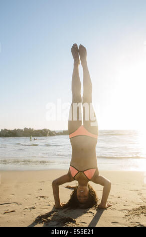 Fit young woman doing headstand on beach Stock Photo