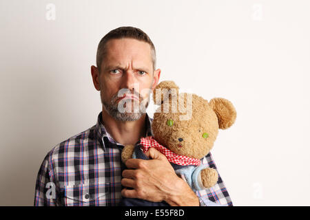 Angry looking man holding a teddy bear Stock Photo
