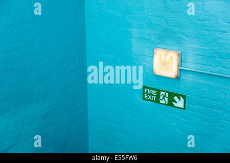 Blue wall corner with emergency exit sign and lamp Stock Photo