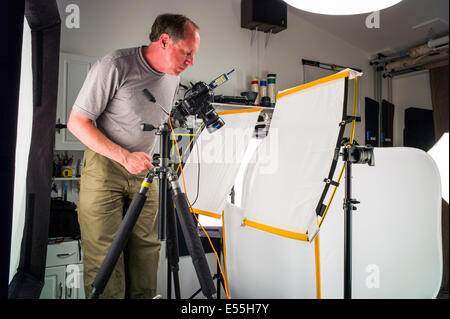 Photographer working on a commercial photography set, including lighting, background and grip gear. Stock Photo