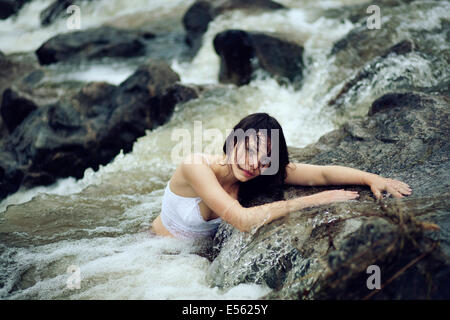 Young woman is sitting in a creek Stock Photo
