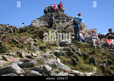 Walkers crowd  onto the summit cairn of Mount Snowdon on a warm summer's day Stock Photo