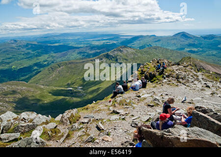 Walkers take a break to admire the view from the summit of Mount Snowdon. Looking southwards over Snowdonia to Cardigan Bay Stock Photo