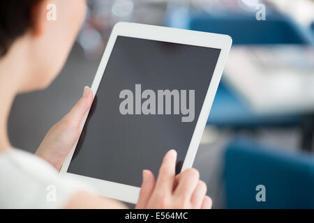 Woman holding and touching on a modern digital tablet and looking on a blank screen. Stock Photo