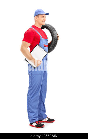 Profile shot of a male mechanic holding a tire and a clipboard Stock Photo