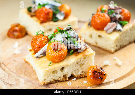 Delicious focaccia with sardines and cherry tomatoes on wood Stock Photo