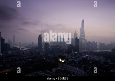 Panoramic wide angle view of the silhouetted skyline of the Financial district of Lujiazui and Pudong with the Jinmao and Shanghai tower seen against the orange light of the rising sun on a clear, blue sky day. © Olli Geibel Stock Photo