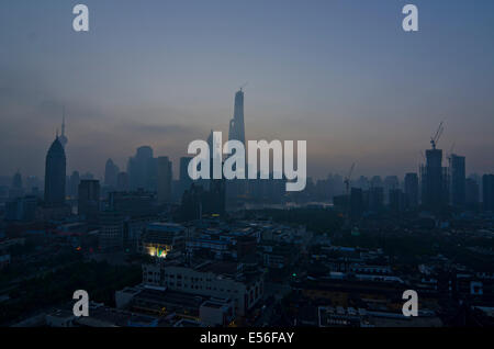Panoramic wide angle view of the silhouetted skyline of the Financial district of Lujiazui and Pudong with the Jinmao and Shanghai tower seen against the orange light of the rising sun on a clear, blue sky day. © Olli Geibel Stock Photo