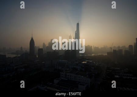 Panoramic wide angle view of the silhouetted skyline of the Financial district of Lujiazui and Pudong with the Jinmao and Shanghai tower seen against the orange light of the rising sun on a clear, blue sky day. © Olli Geibel Stock Photo