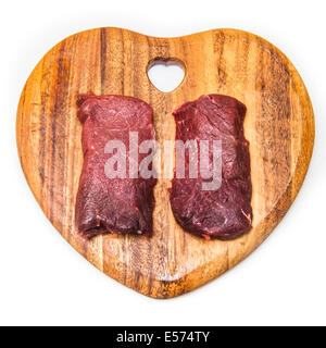 Camel meat steaks on a wooden chopping board isolated on a white studio background. Stock Photo