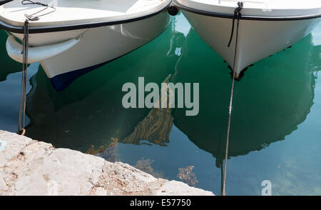 Emerald water is under bottoms of boats that are floating near the pier. Stock Photo