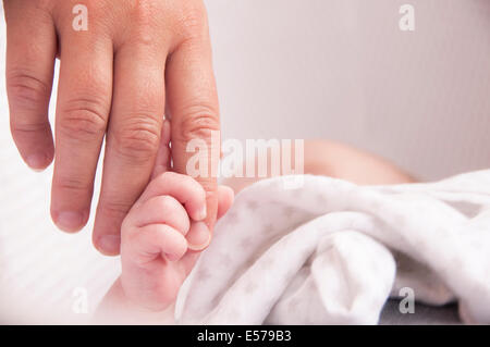 Baby holding mothers hand for reassurance in his nursery Stock Photo