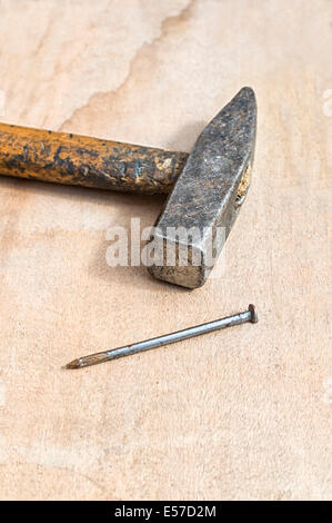 Hammer and nail on wooden board. Selective focus on hammer. Stock Photo