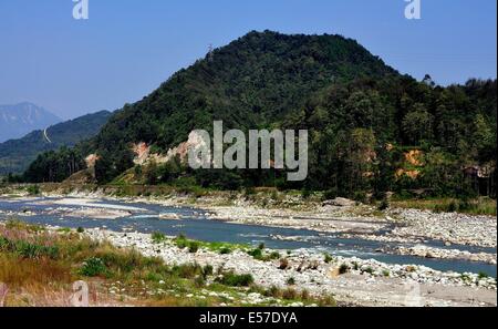 XIN XING TOWN, CHINA:  The rocky Jian Jiang River lined by verdant hills of deciduous trees and bamboo Stock Photo