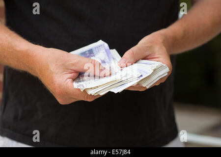 Handing over UK cash notes. Counting money maybe about to pay in cash.Money is UK cash sterling. Stock Photo