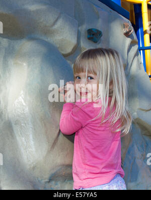 Young Caucasian girl playing in the park. She is wearing a pink t-shirt and blue skirt. Stock Photo