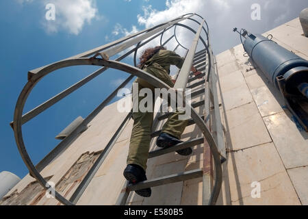 An Israeli soldier from the Field Intelligence Corps climbs to the roof of a residential building in the city of Beersheba to identify locations that were hit by rockets fired from Gaza strip. The Field Intelligence Corps, is responsible for collecting visual information on the battlefield and rapidly transferring it to other forces. Stock Photo