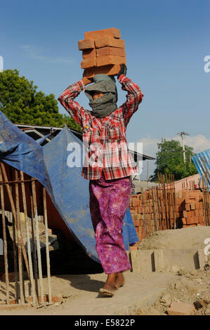 Female construction worker carry bricks on their heads, high rise construction site, Mandalay, Myanmar Stock Photo