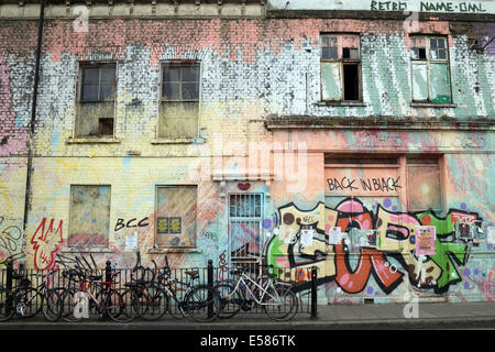 A building which has been painted with various hues of paint, also featuring some graffiti tags and bicycles chained to railings Stock Photo