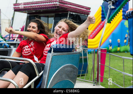 Two young girls enjoying themselves on a fairground ride at the Brentwood Festival in Essex. Stock Photo