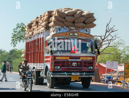 Overloaded dump truck filled with jute bags on the road. Stock Photo