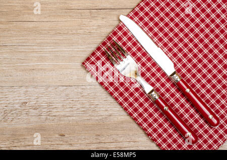 Knife and fork with red checkered napkin on a wooden table Stock Photo