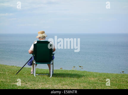 Elderly lady reading and enjoying the warm weather at Whitby, North Yorkshire, England, UK Stock Photo