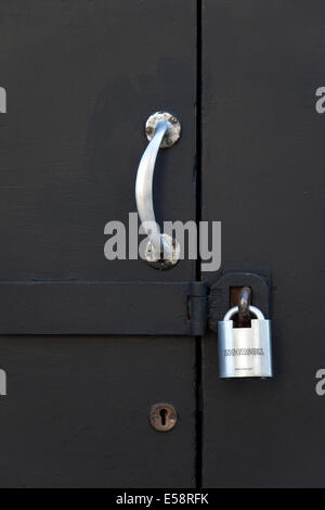 Closeup black of door with handle and padlock Stock Photo