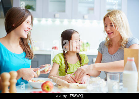 Portrait of happy girls helping their mother to cook pastry Stock Photo