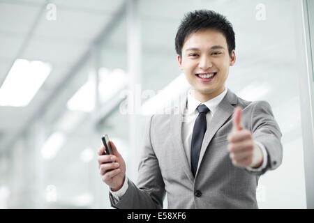 Young businessman giving thumbs up Stock Photo